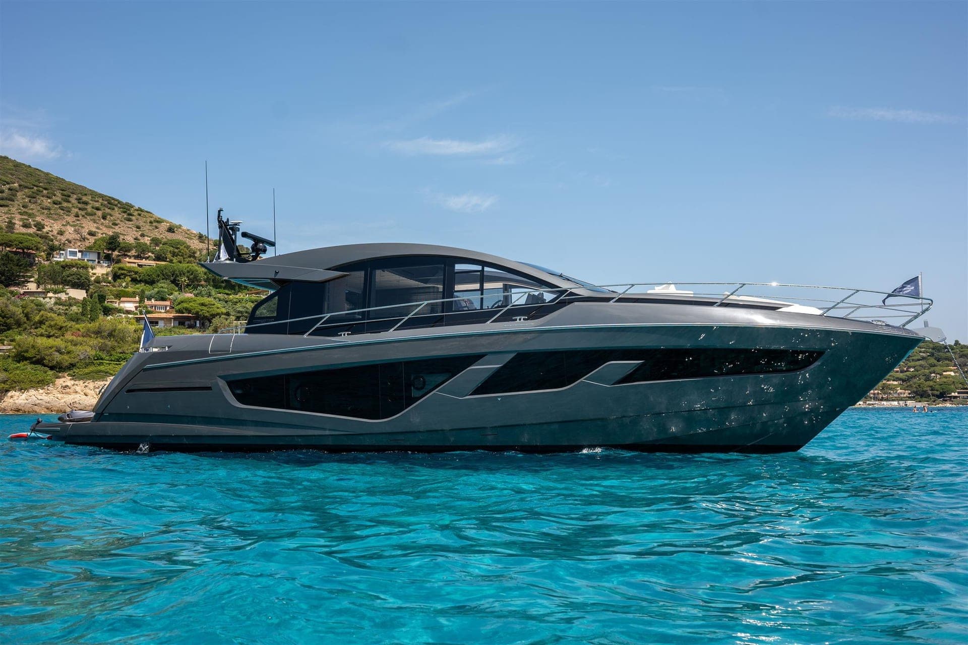 Sunseeker Predator 65 à coque grise au mouillage devant une côte méditerranéenne, vue de profil